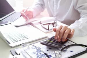 Doctor working at desk with computer and phone.