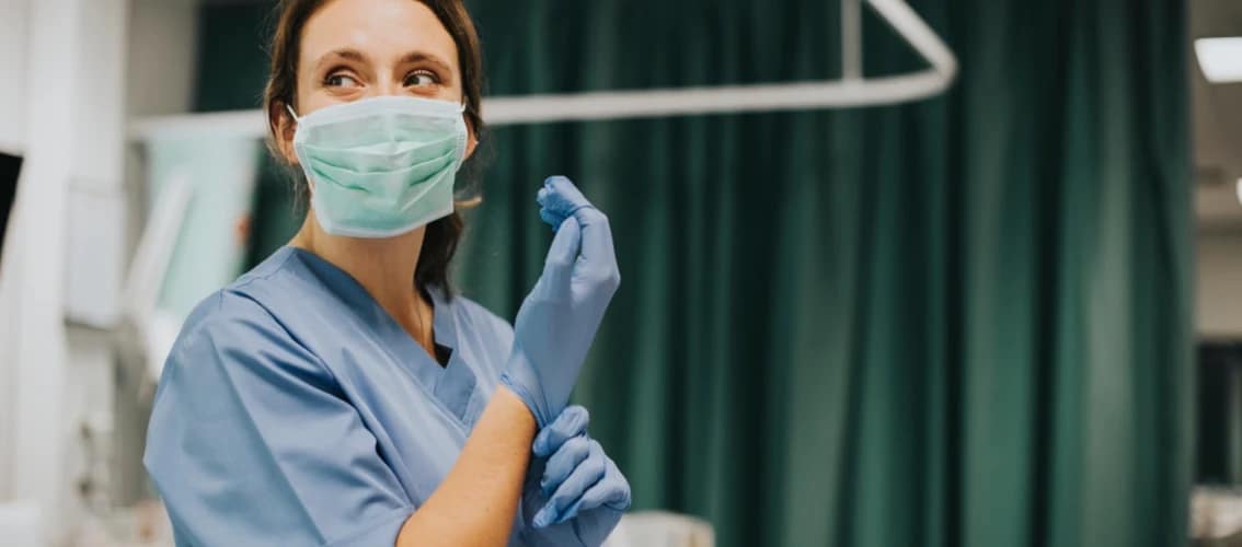 Female physician puts on personal protective equipment