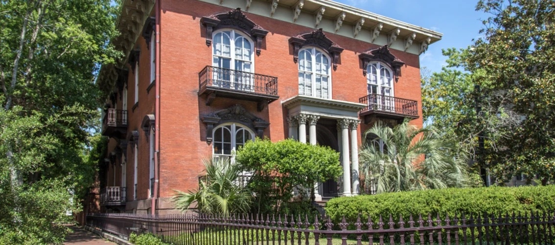 antebellum brick two story home with iron fence