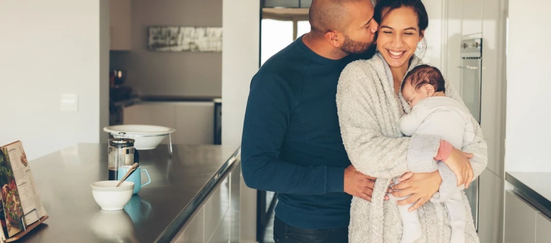 Happy physician couple in their kitchen with baby