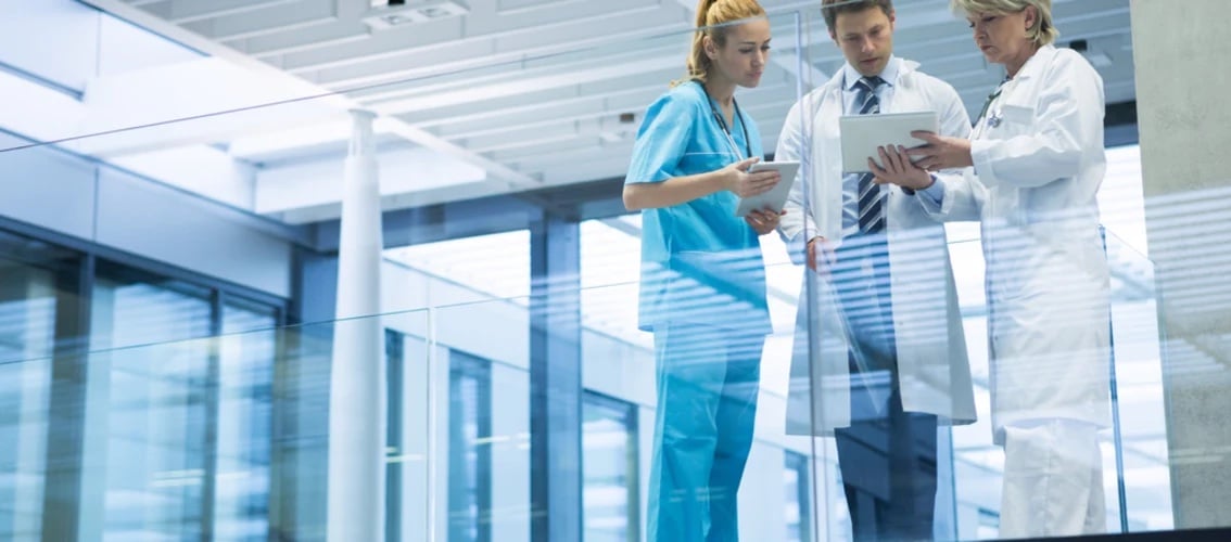 Three physicians compare notes in hallway