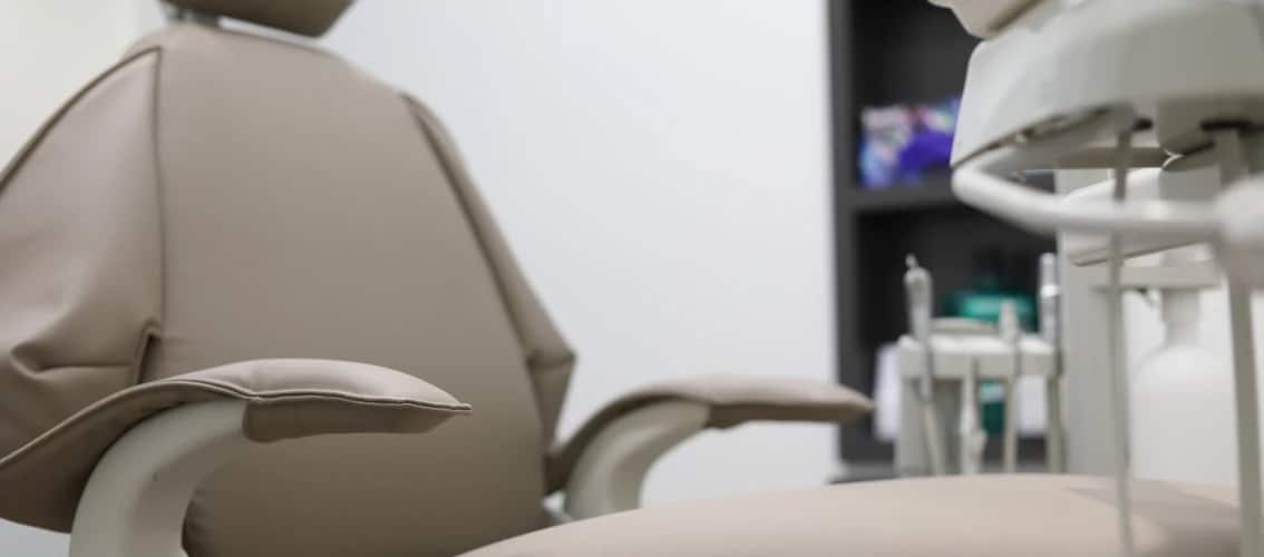 View of an exam chair and tools in a dental office.