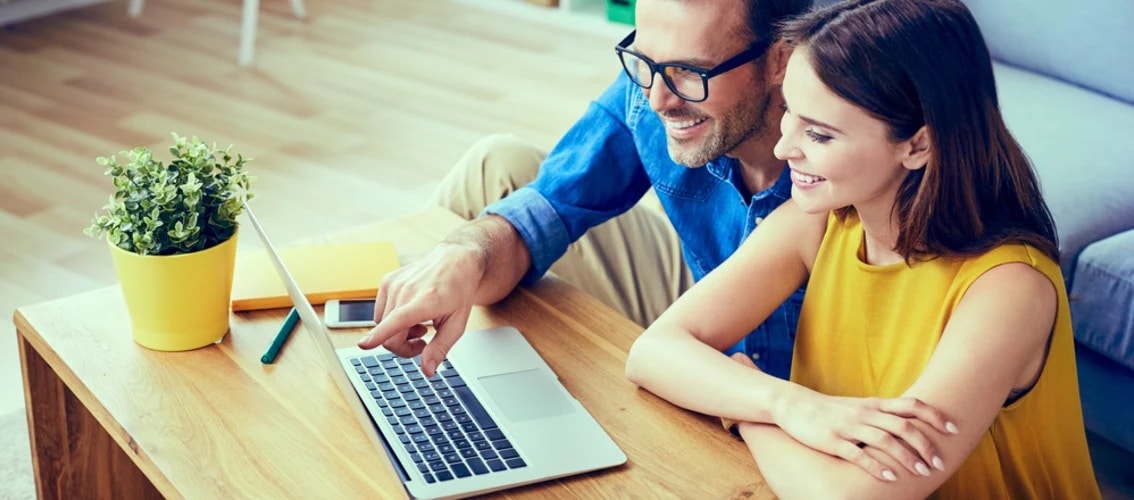 Happy couple looks at options on a laptop