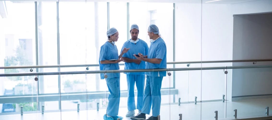 Three physicians compare notes in a hallway