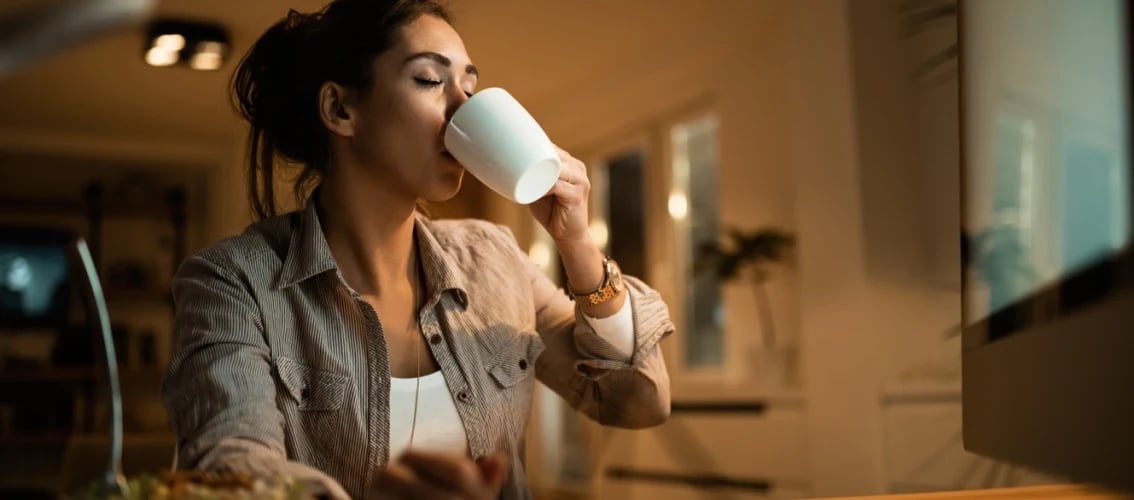 Physician drinking coffee at a computer