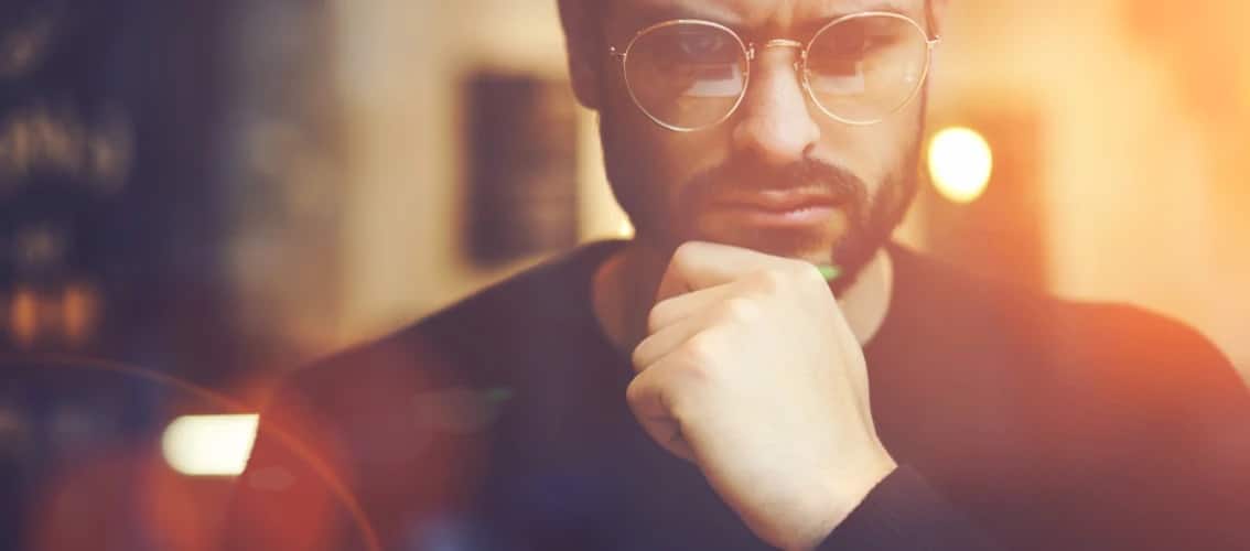 A male physician with glasses looks determined.