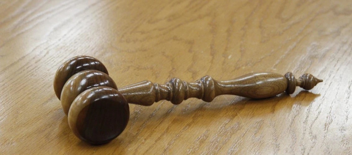 Wooden gavel sits on a wooden table.