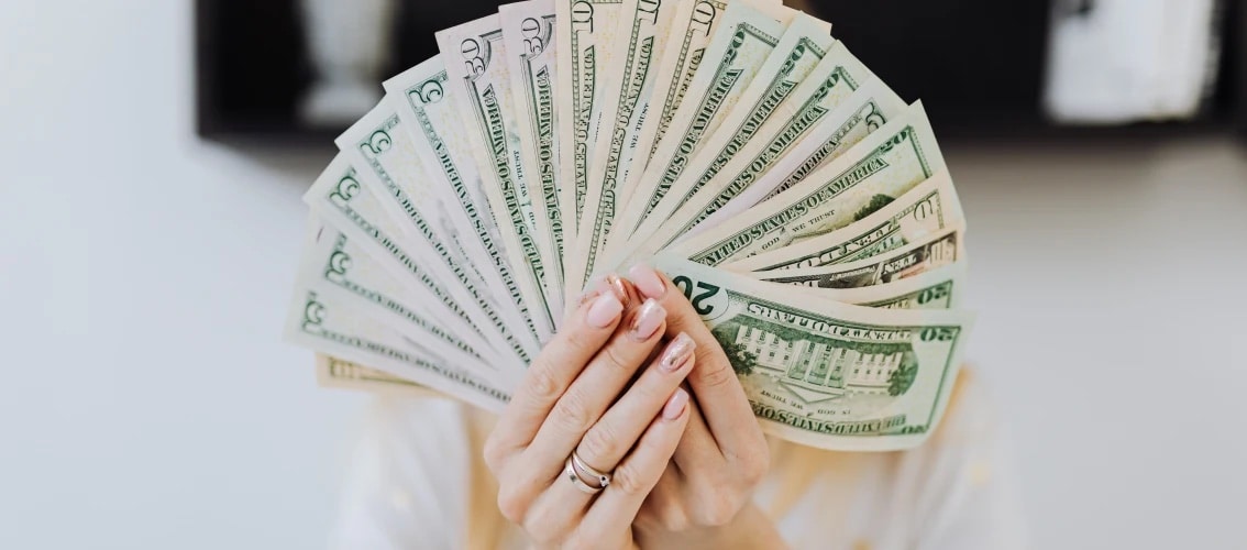 Female hands hold a large fan of US cash.
