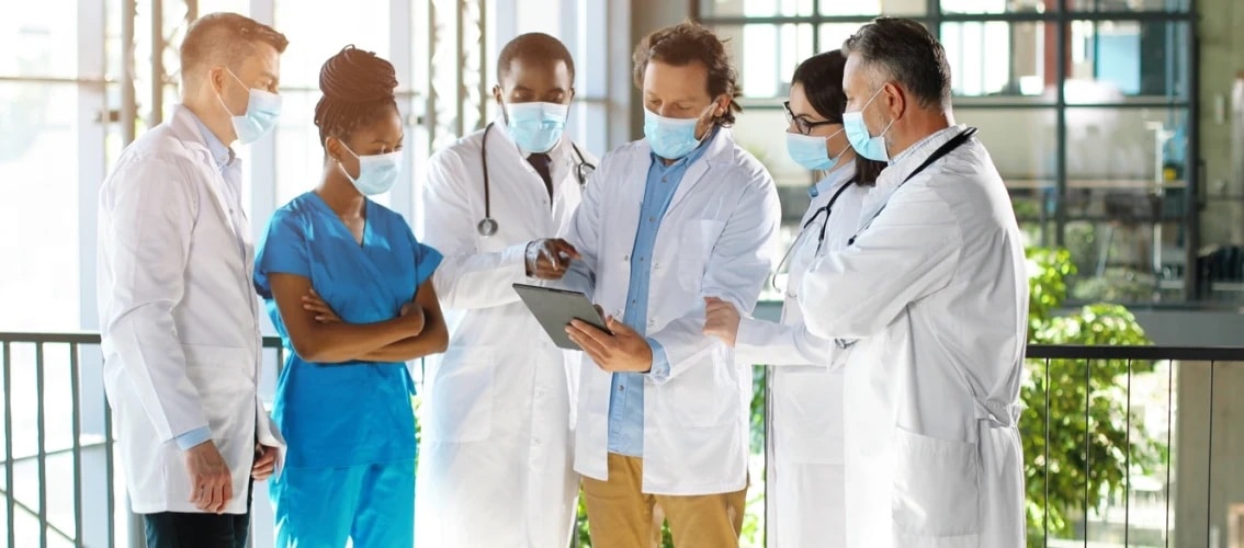 Group of masked physicians reviewing patient records