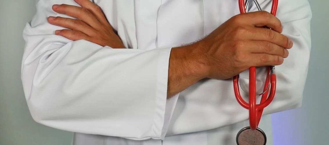 a doctor in whites coat folds arms