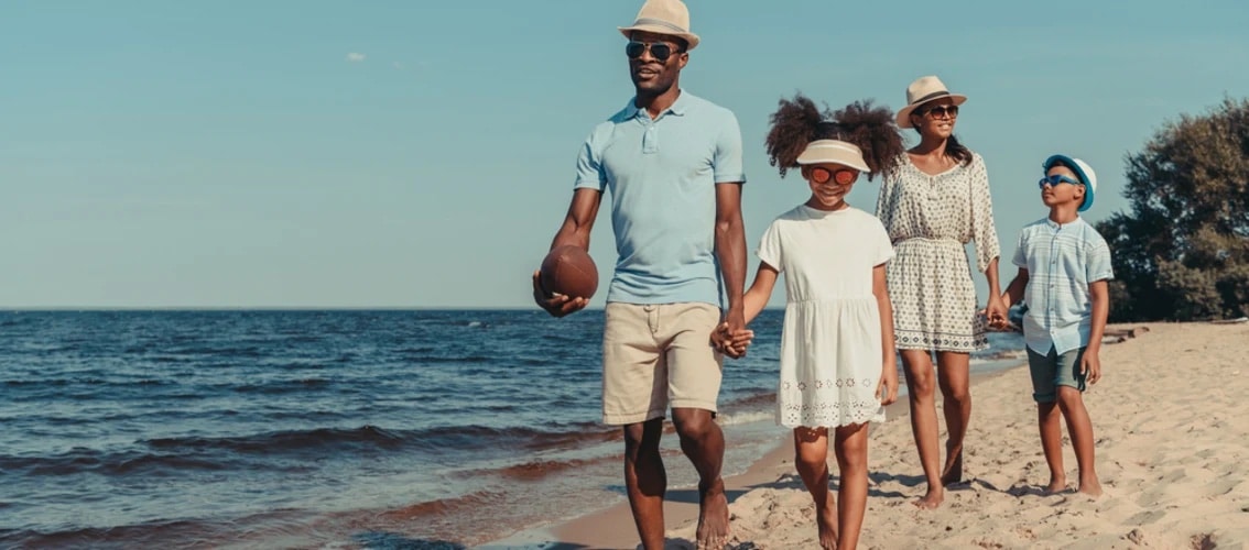 A happy family walks down a beach while on vacation