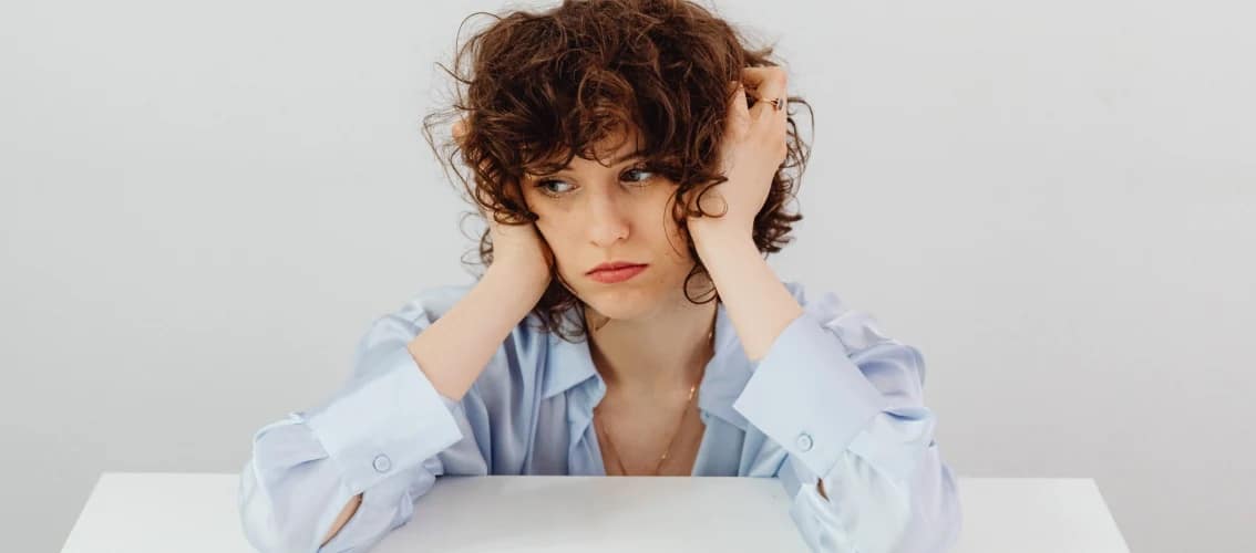 A female physician looks troubled and holds her head.