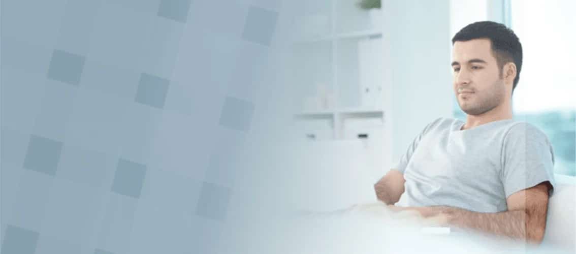 Male physician sits on his couch with laptop