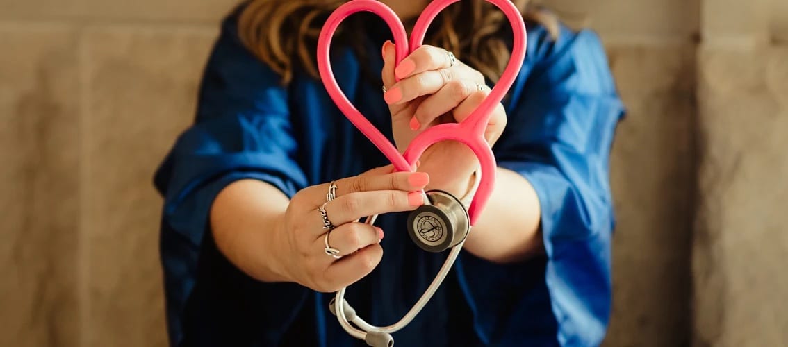 Female physician holds a stethoscope in the shape of a heart.