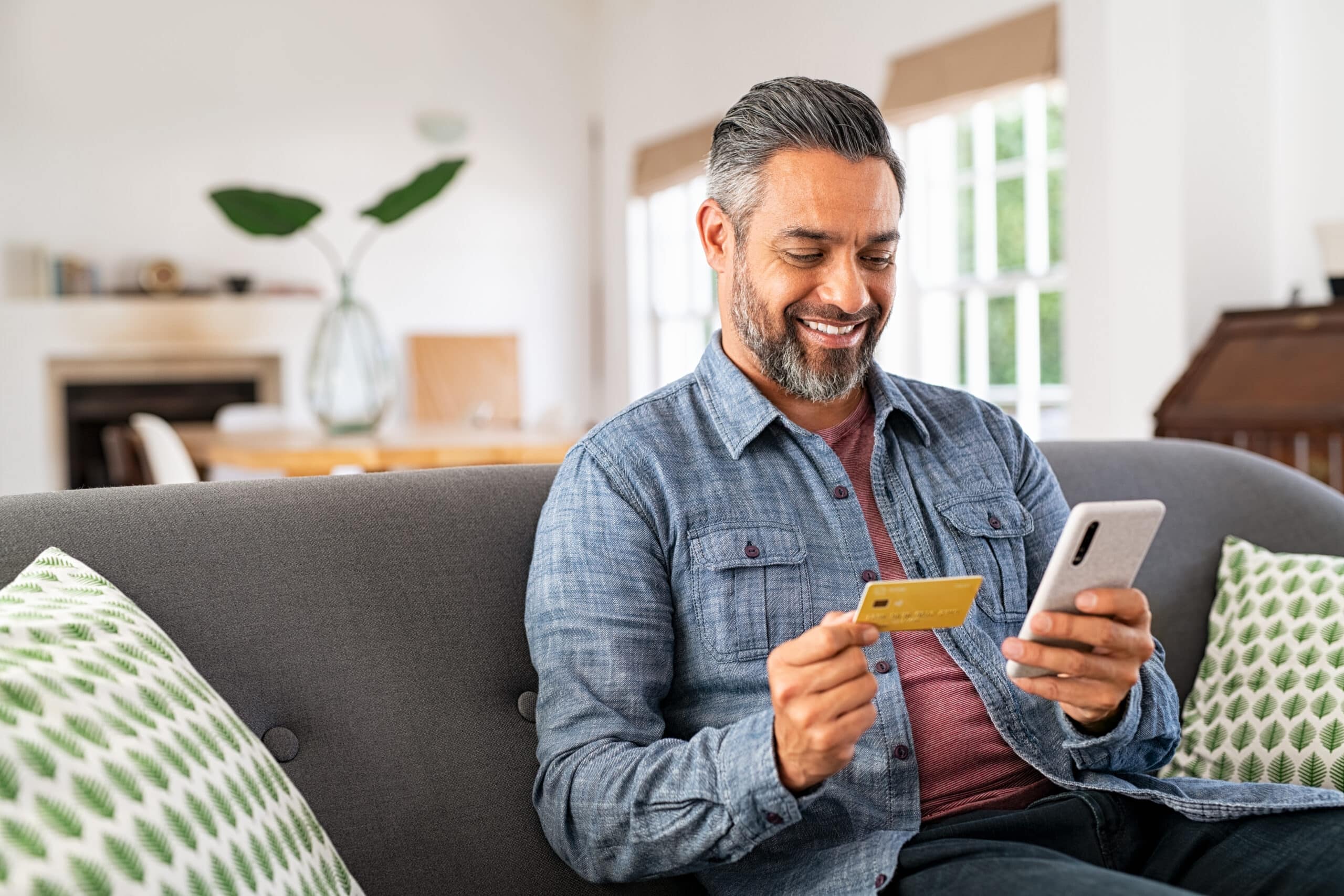 Doctor looks at a credit card and his phone and smiles.