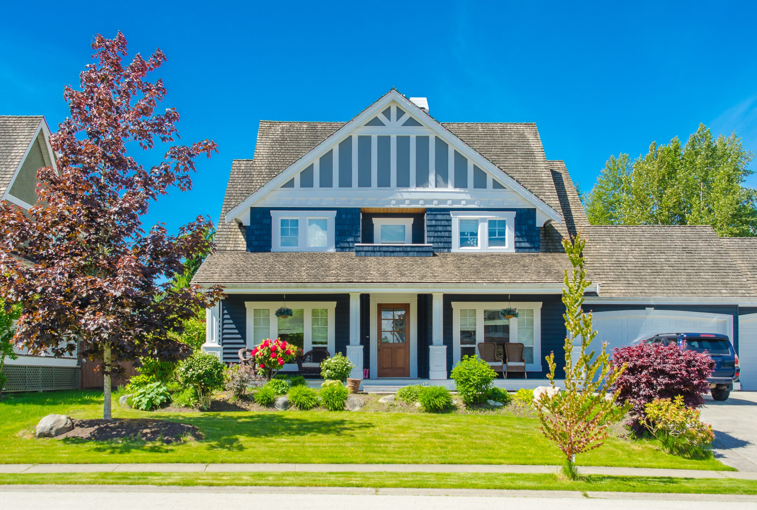 Two story blue wood shingle home in a neighborhood.