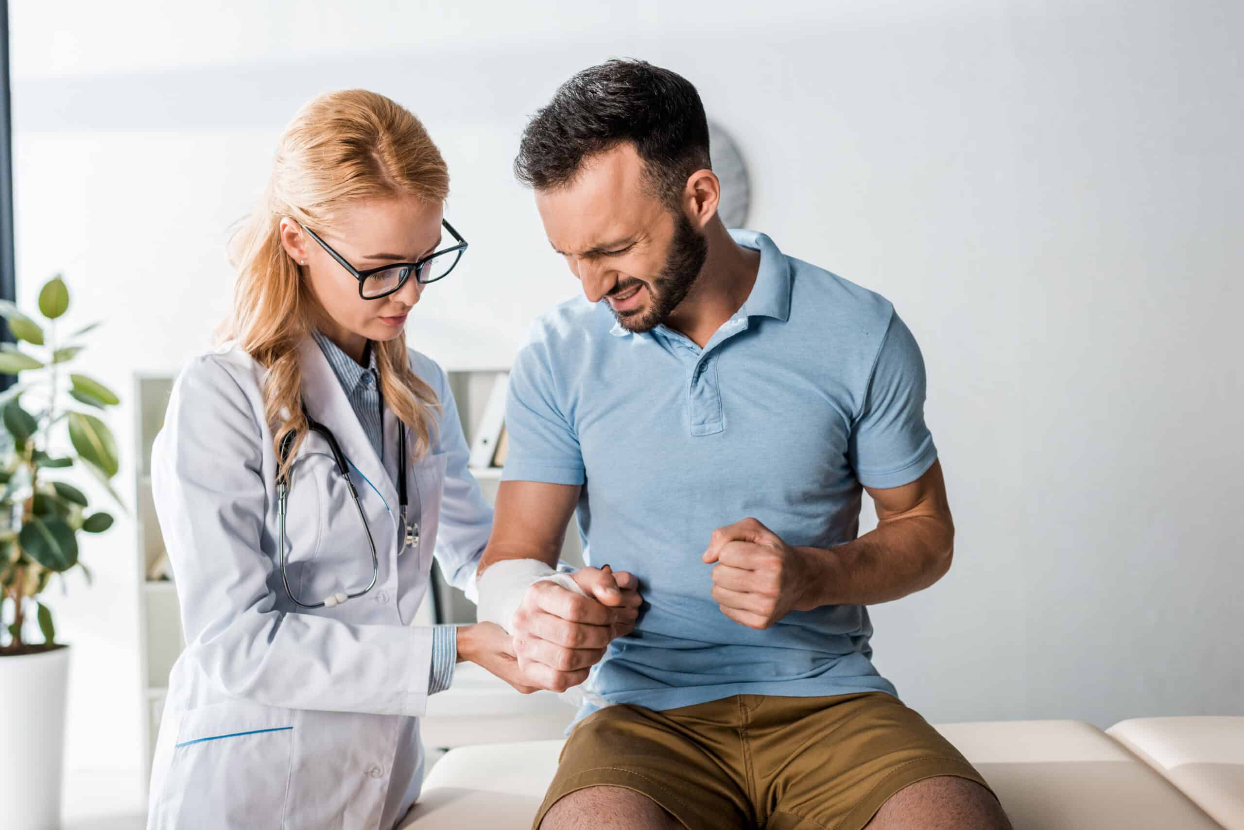 A female doctor helps a male patient put a cast on his arm