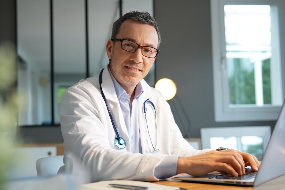 Happy physician working at a computer.