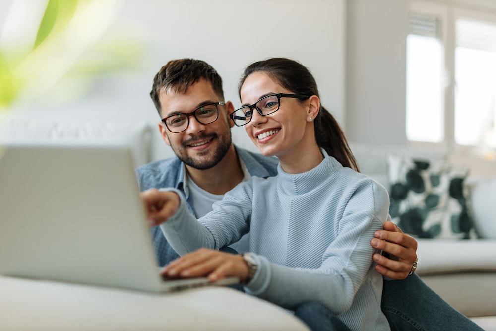 A happy couple looks at finances on a laptop.