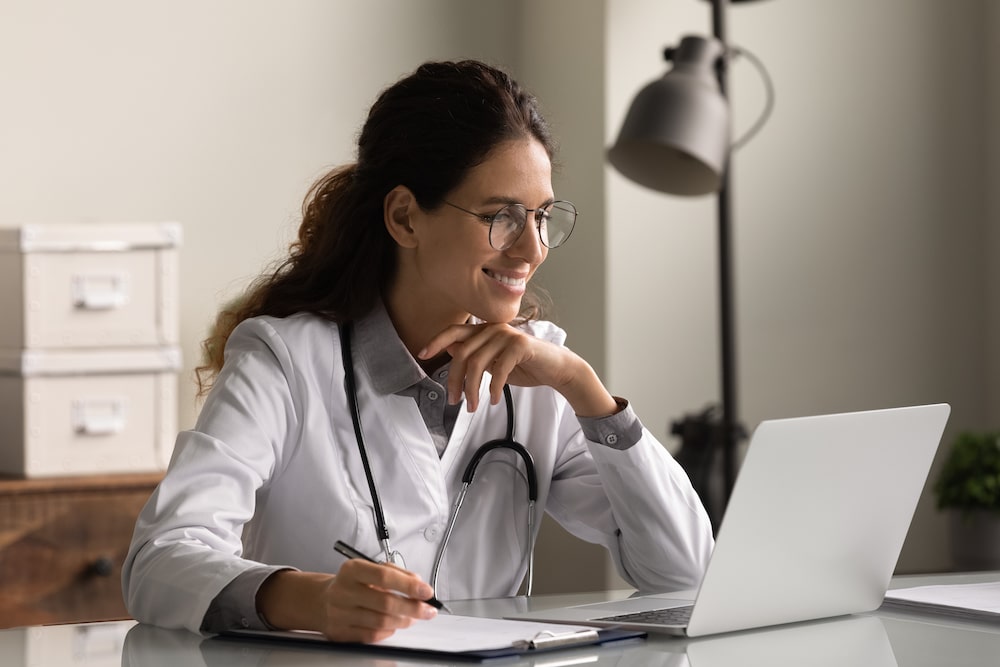 Female physician works on her laptop in her office.