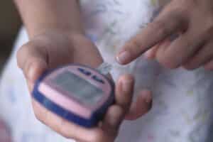 a female checks her blood sugar with a device.