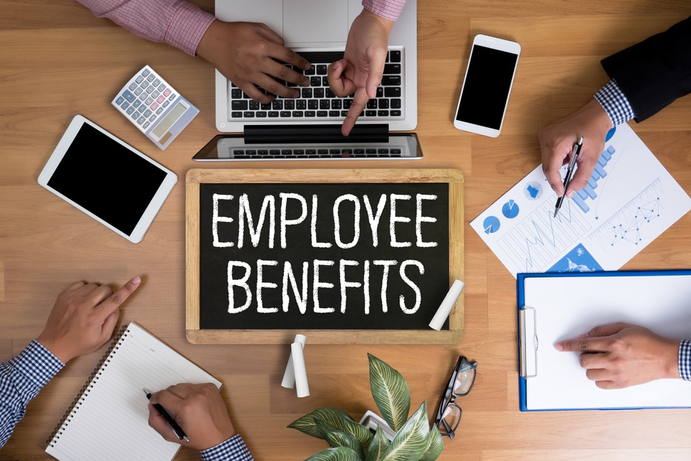 Top-down view of three co-workers setting at a meeting table discussing benefits