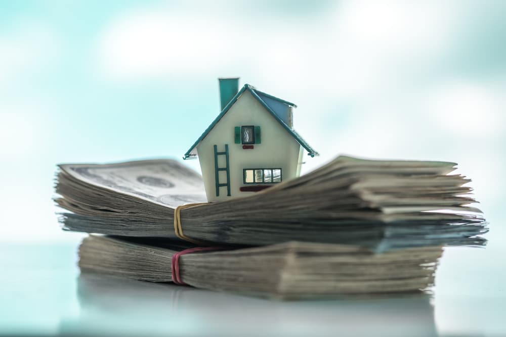 model home on top of a stack of cash