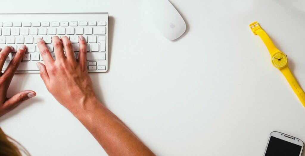 hands type on a computer keyboard