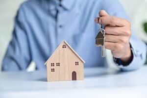 a physician holds the keys to a new home next to a small model of a house