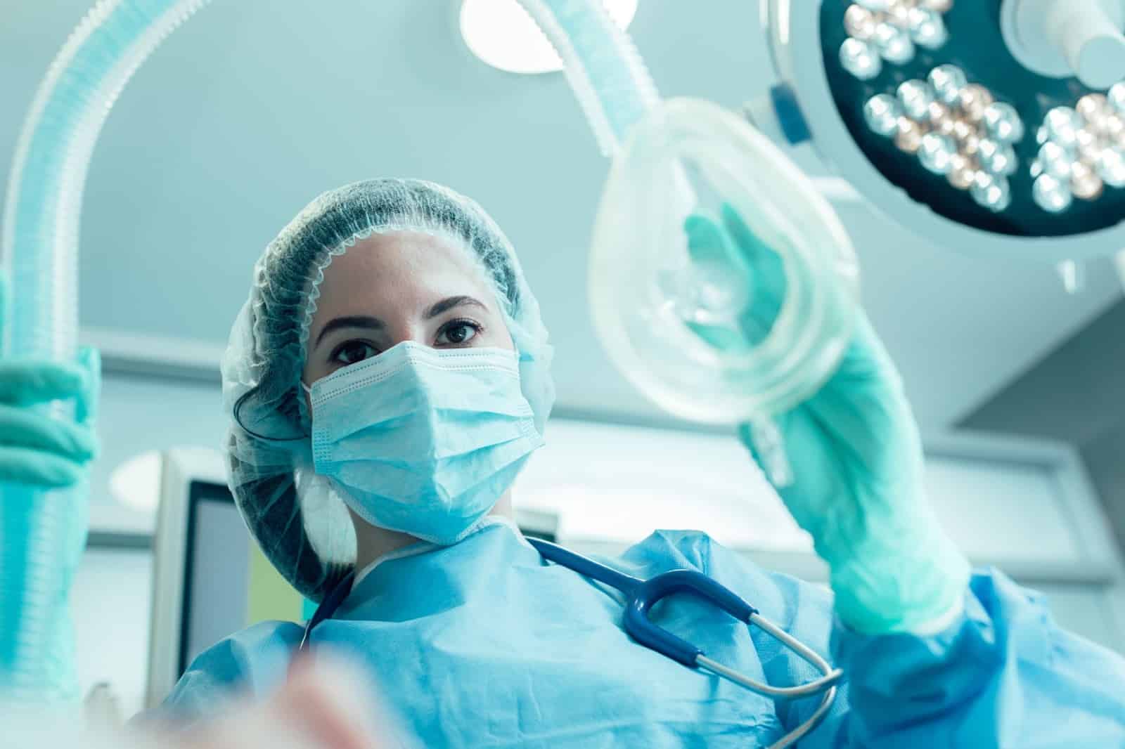 An anesthesiologist places a gas mask on patient.